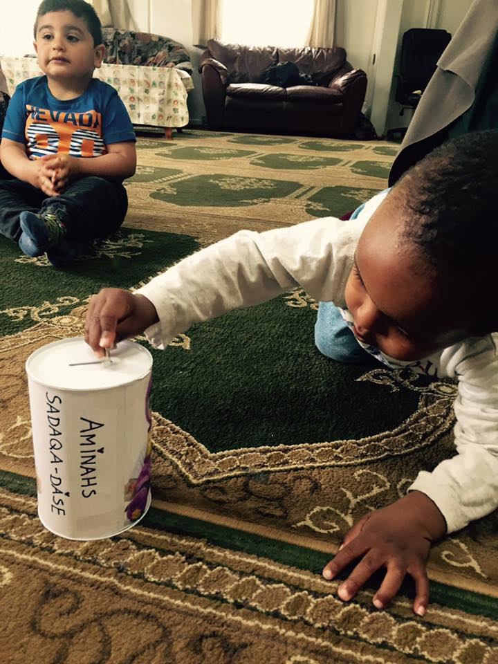Lille dreng putter penge i en dåse i moske